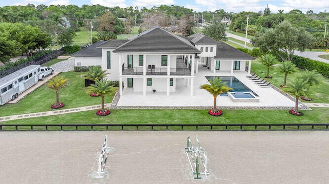 rear view of property featuring a fenced in pool, a yard, a patio, and a balcony