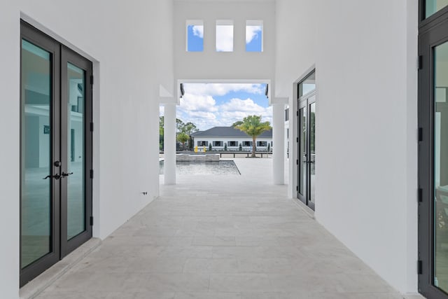 hall with french doors, a water view, and a high ceiling