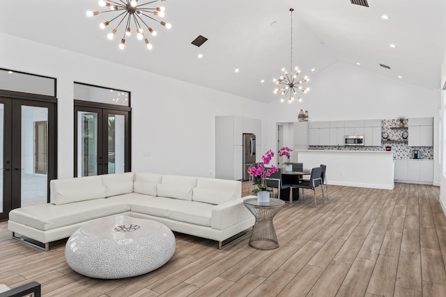 living room with a notable chandelier, high vaulted ceiling, and french doors