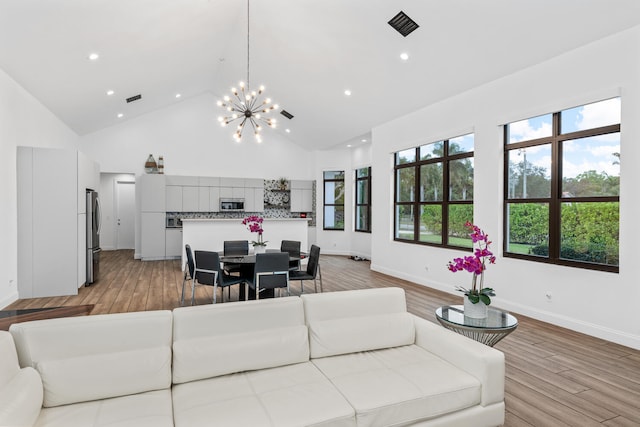 living room with light wood-type flooring, a chandelier, and high vaulted ceiling