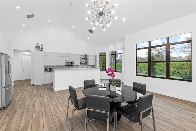 dining area with high vaulted ceiling, light hardwood / wood-style flooring, and a notable chandelier