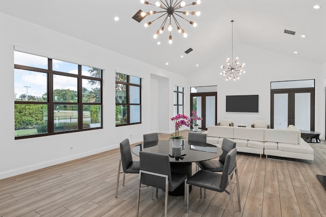 dining area featuring a notable chandelier, a towering ceiling, and french doors