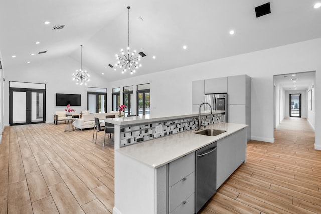 kitchen with a large island, sink, appliances with stainless steel finishes, gray cabinetry, and hanging light fixtures