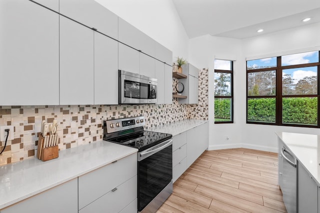 kitchen with white cabinetry, tasteful backsplash, vaulted ceiling, and appliances with stainless steel finishes