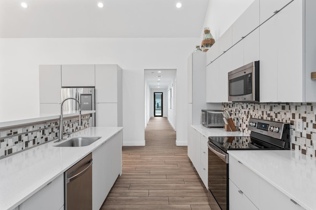 kitchen featuring stainless steel appliances, tasteful backsplash, sink, and white cabinetry