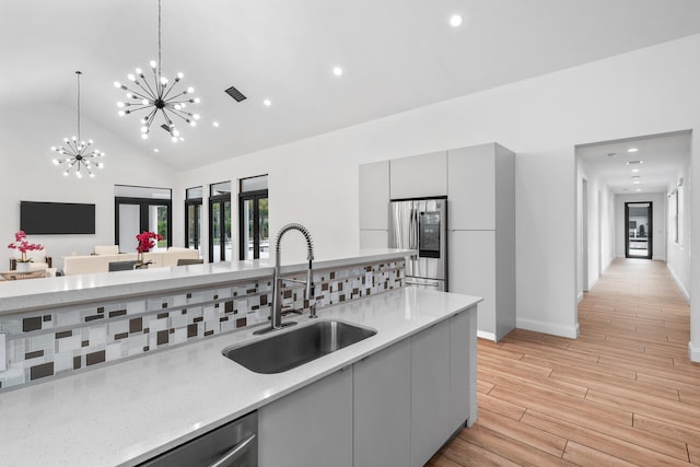 kitchen featuring sink, gray cabinetry, stainless steel appliances, decorative light fixtures, and a chandelier