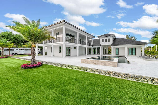 back of house featuring a swimming pool with hot tub, a balcony, a lawn, and a patio area