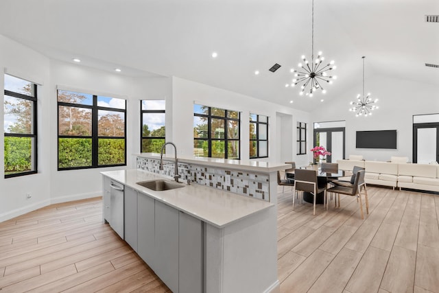 kitchen featuring sink, a chandelier, hanging light fixtures, stainless steel dishwasher, and a large island