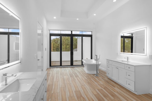 bathroom with hardwood / wood-style floors, vanity, plenty of natural light, and a bath