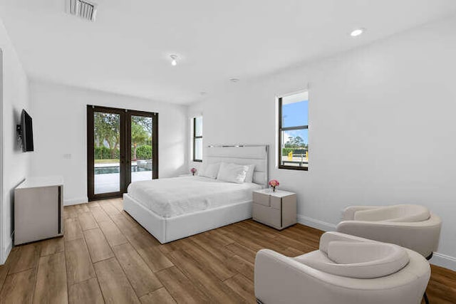 bedroom with access to exterior, light hardwood / wood-style floors, and french doors