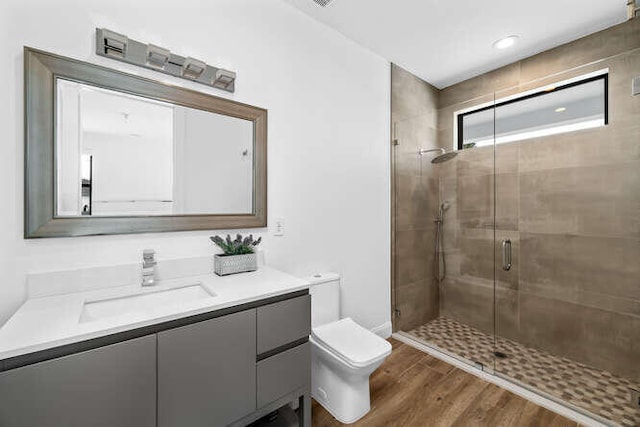 bathroom with vanity, wood-type flooring, a shower with shower door, and toilet