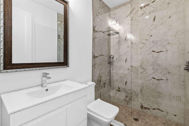 bathroom featuring vanity, toilet, and a tile shower