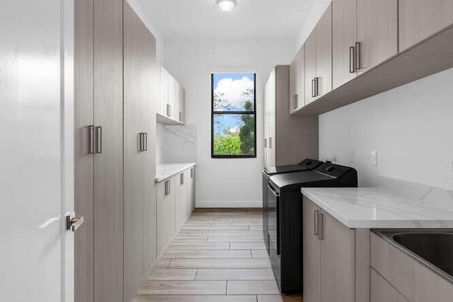 laundry area featuring cabinets, separate washer and dryer, and sink