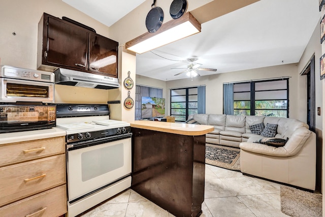 kitchen featuring dark brown cabinetry, light tile patterned floors, kitchen peninsula, ceiling fan, and white range oven