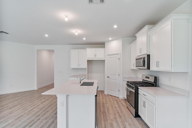 kitchen with sink, appliances with stainless steel finishes, a kitchen island with sink, light hardwood / wood-style floors, and white cabinets