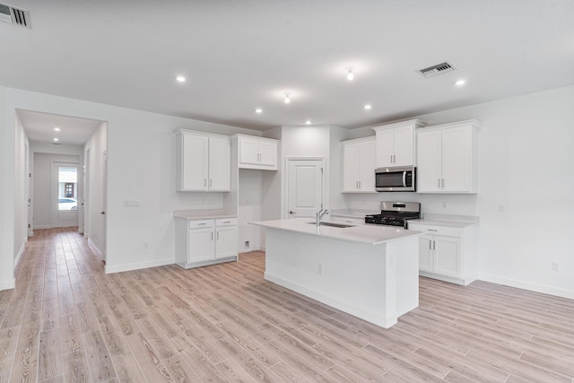 kitchen featuring white cabinetry, appliances with stainless steel finishes, and an island with sink