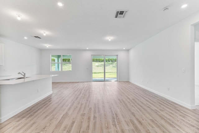 unfurnished living room with sink and light hardwood / wood-style flooring