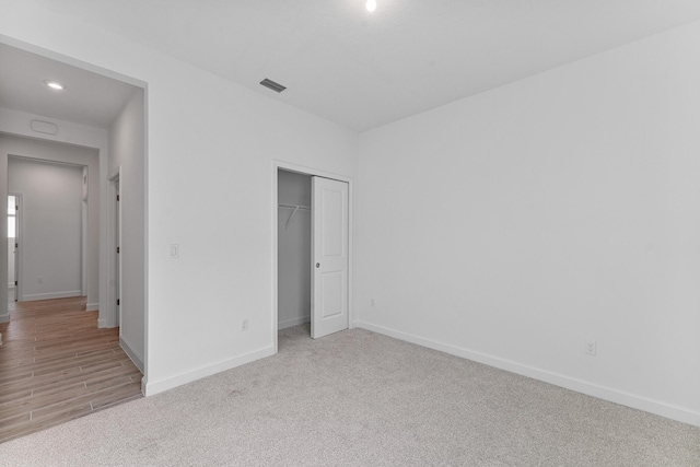 unfurnished bedroom with light carpet and a closet