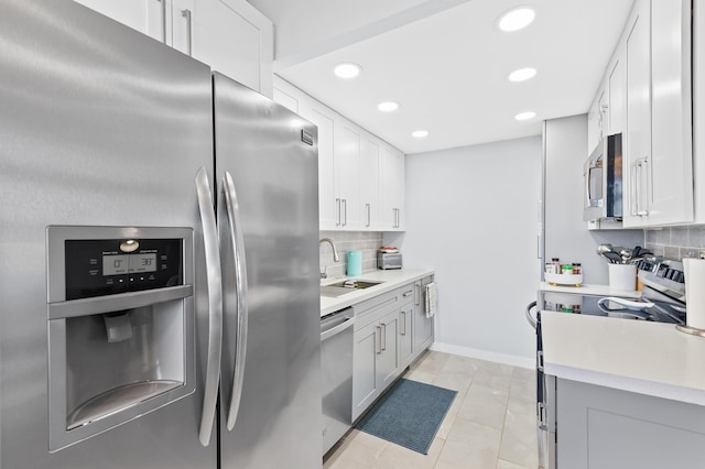 kitchen with sink, light tile patterned floors, appliances with stainless steel finishes, backsplash, and white cabinets