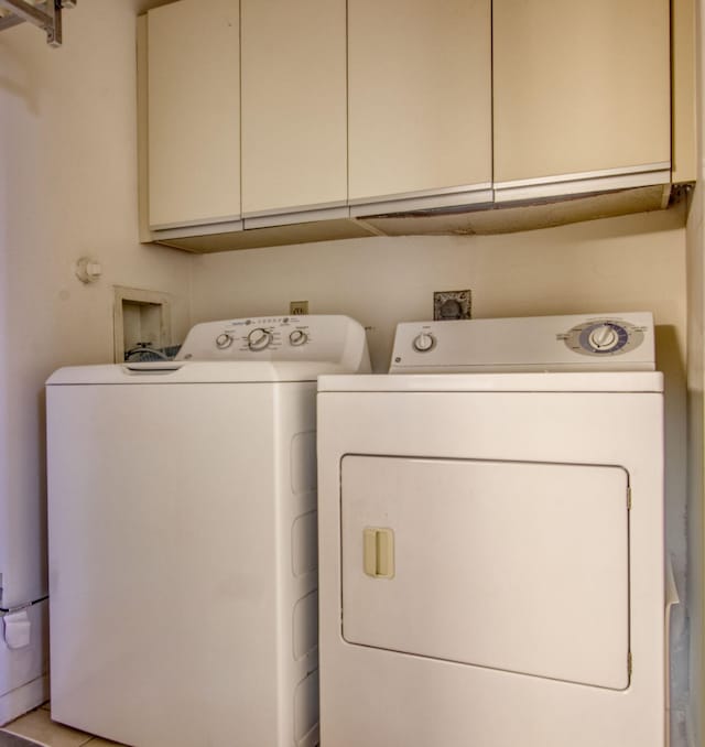 clothes washing area with cabinets and washing machine and clothes dryer