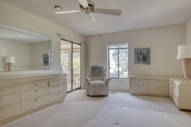 living area with ceiling fan, light colored carpet, and a textured ceiling