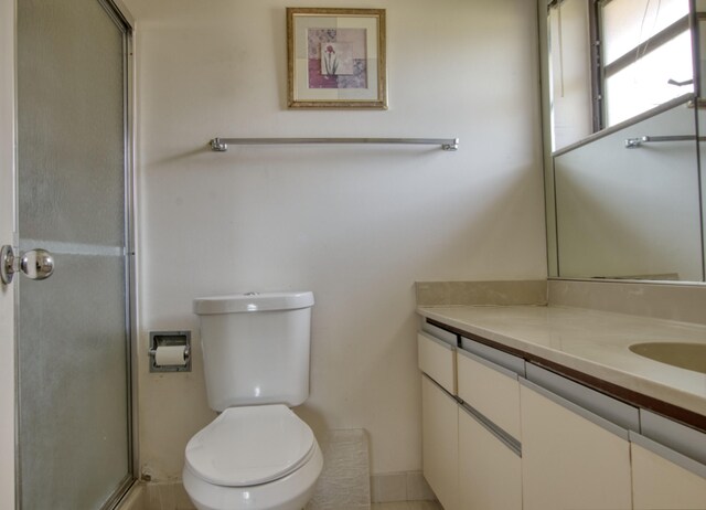 bathroom featuring vanity, a shower with shower door, and toilet