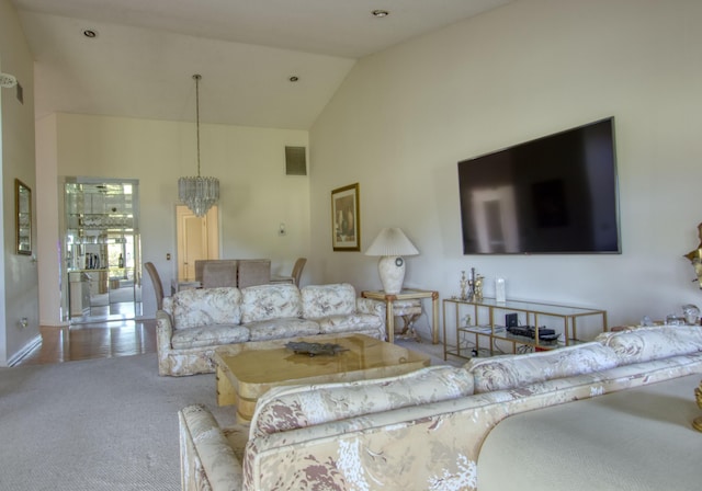 carpeted living room featuring high vaulted ceiling and a chandelier