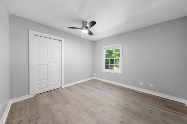 unfurnished bedroom featuring a textured ceiling, light hardwood / wood-style floors, a closet, and ceiling fan