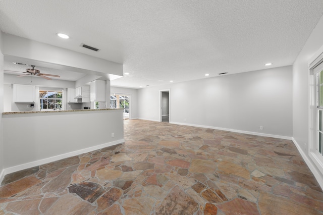 living room featuring ceiling fan and a textured ceiling