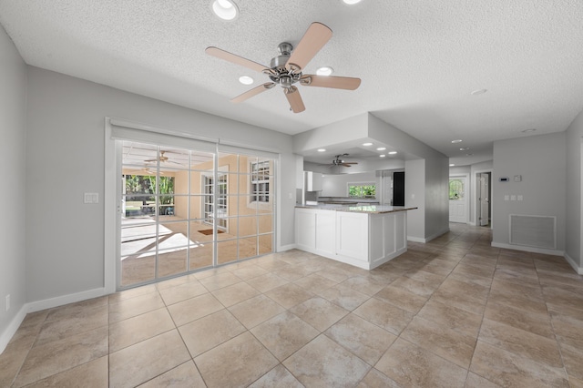 kitchen featuring light tile patterned flooring, white cabinets, a textured ceiling, and kitchen peninsula