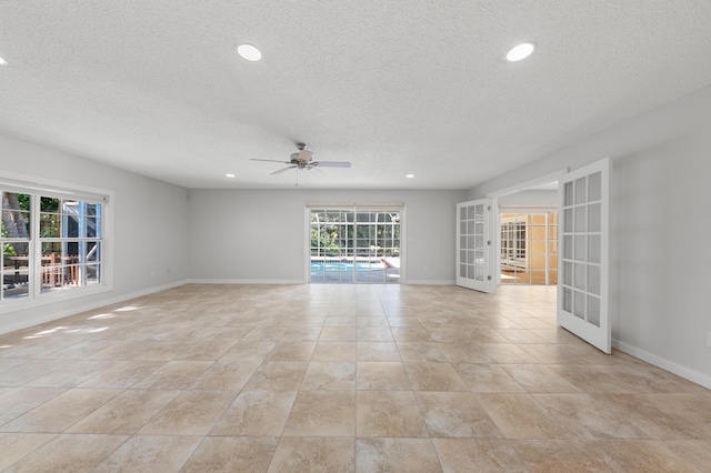 empty room with ceiling fan, a textured ceiling, and french doors