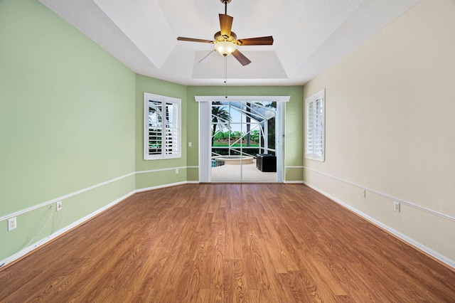 spare room with hardwood / wood-style flooring, a raised ceiling, and ceiling fan