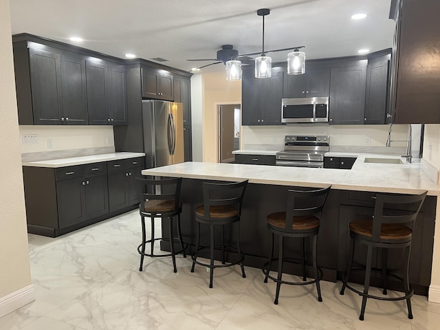 kitchen with appliances with stainless steel finishes, a kitchen bar, kitchen peninsula, and sink