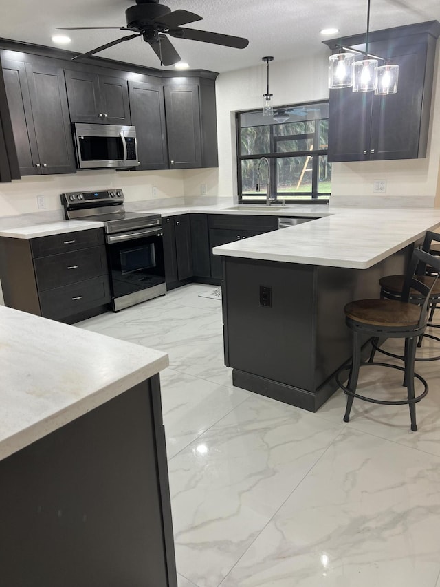 kitchen featuring appliances with stainless steel finishes, a breakfast bar, pendant lighting, sink, and kitchen peninsula