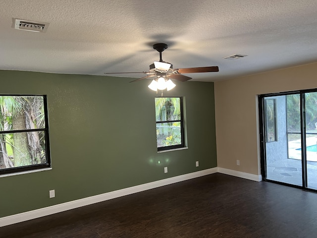 empty room with ceiling fan, plenty of natural light, a textured ceiling, and dark hardwood / wood-style flooring