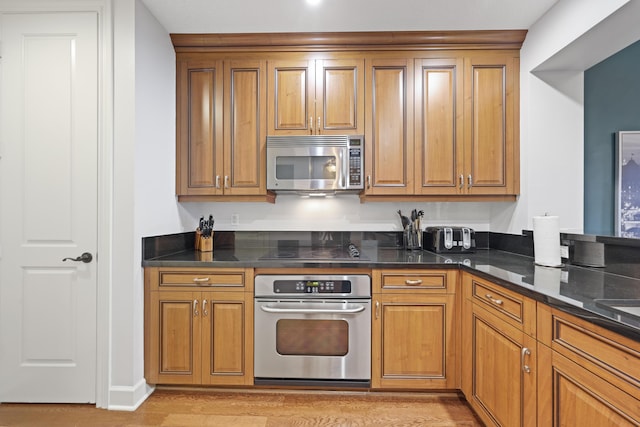 kitchen featuring stainless steel appliances, dark stone countertops, and light hardwood / wood-style flooring