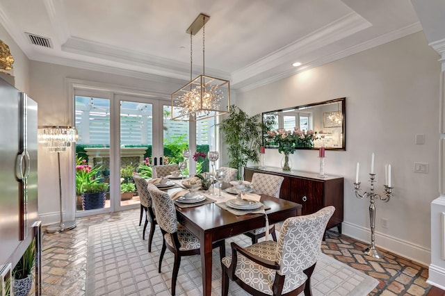 dining room featuring crown molding, a raised ceiling, and decorative columns