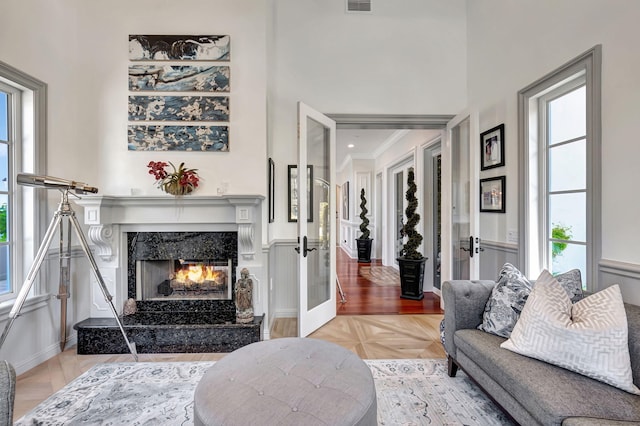 living room featuring french doors, parquet flooring, a healthy amount of sunlight, and a fireplace