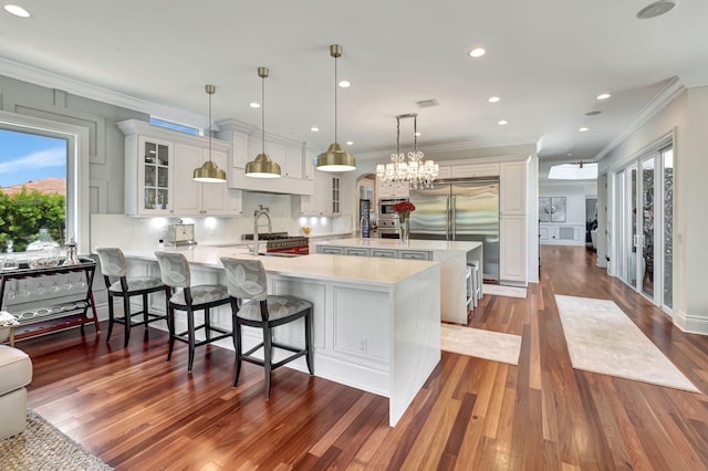 kitchen featuring hanging light fixtures, white cabinetry, a breakfast bar, and a healthy amount of sunlight