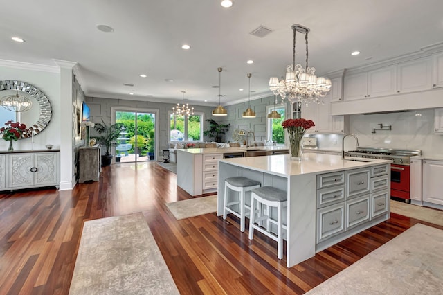 kitchen featuring decorative light fixtures, white cabinets, a kitchen breakfast bar, stove, and a spacious island