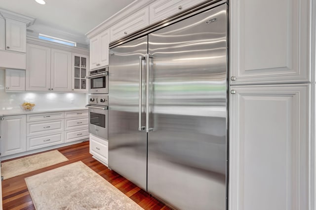 kitchen with stainless steel appliances, dark hardwood / wood-style flooring, and white cabinets