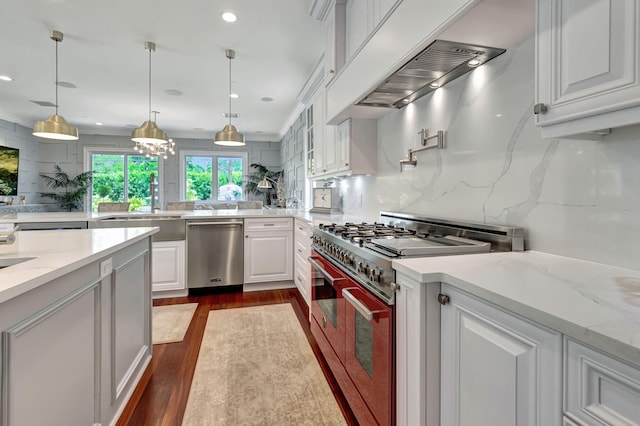 kitchen with appliances with stainless steel finishes, dark hardwood / wood-style floors, white cabinetry, hanging light fixtures, and light stone countertops