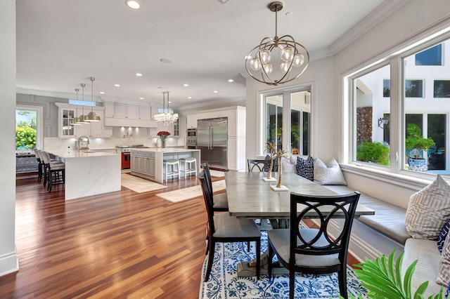 dining area featuring hardwood / wood-style flooring, ornamental molding, sink, and a notable chandelier