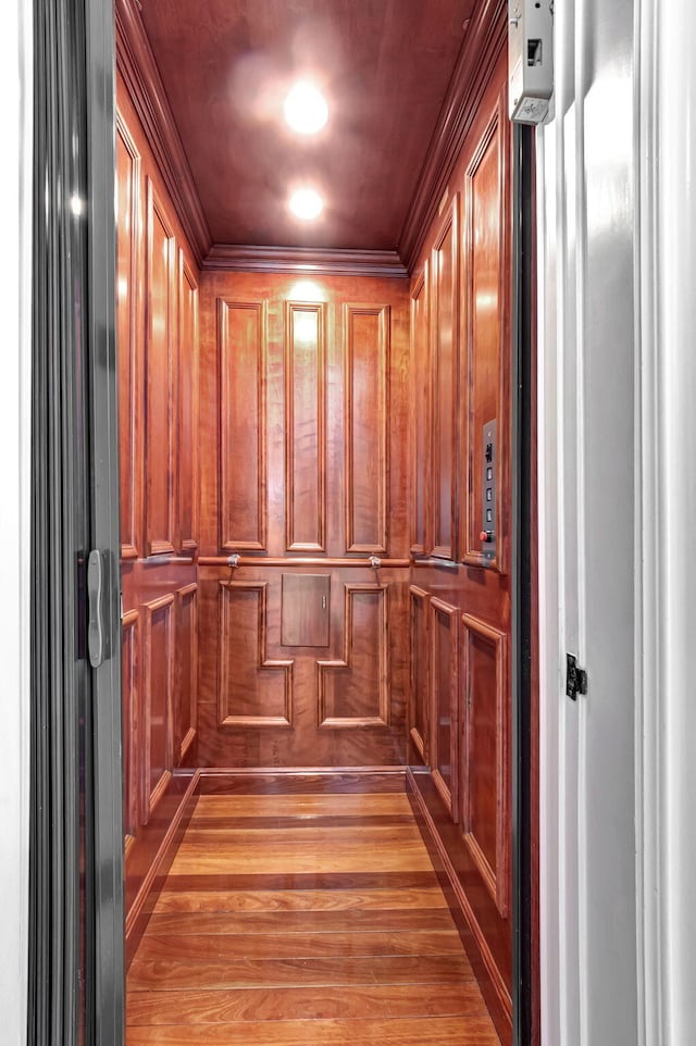 details with wooden walls, ornamental molding, and elevator