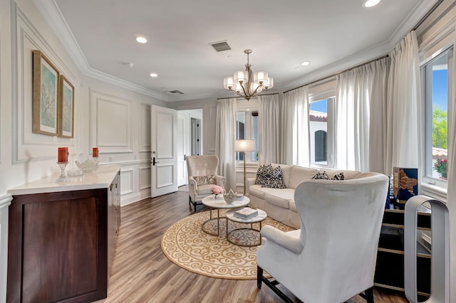 living room featuring ornamental molding, an inviting chandelier, and light hardwood / wood-style flooring