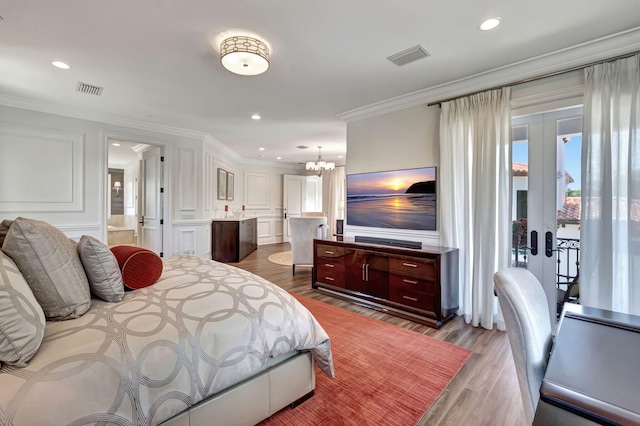 bedroom featuring french doors, crown molding, ensuite bath, an inviting chandelier, and light hardwood / wood-style flooring