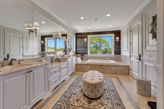 bathroom featuring a notable chandelier, vanity, ornamental molding, and tiled tub