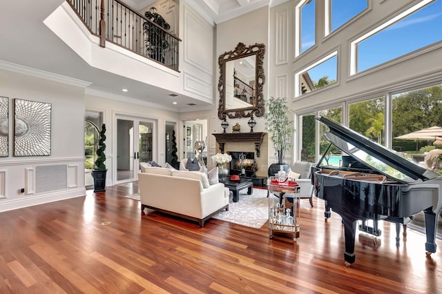 sitting room featuring crown molding, a towering ceiling, hardwood / wood-style floors, and french doors