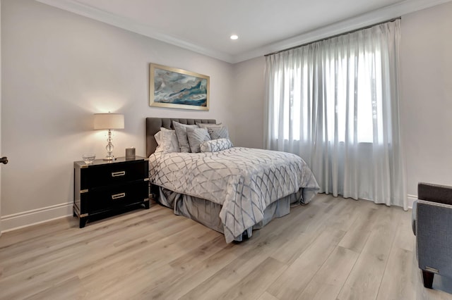 bedroom featuring multiple windows, crown molding, and light wood-type flooring