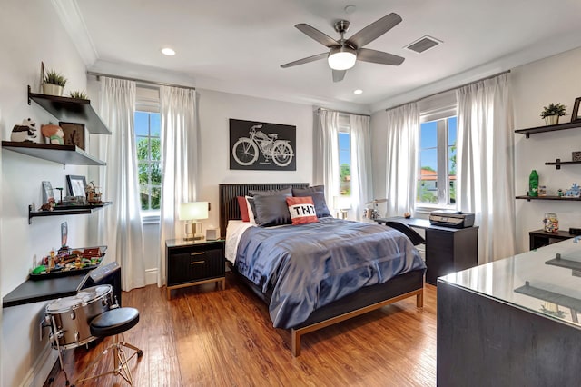 bedroom with hardwood / wood-style floors, ornamental molding, and ceiling fan